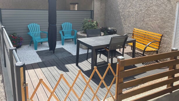 En patio med et bord, stole og en bænk.