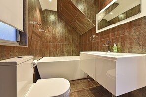 A modern bathroom with a toilet, bathtub, and sink.