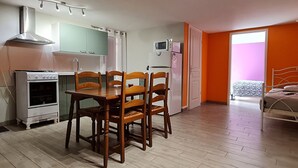 Une cuisine compacte comprenant une table et des chaises, un four à micro-ondes et un réfrigérateur.