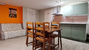 Un espace de vie compact comprenant un coin repas, une kitchenette et un canapé.