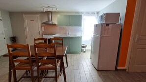 Une cuisine de taille réduite comprenant une table et des chaises, un fourneau, un évier et un réfrigérateur.