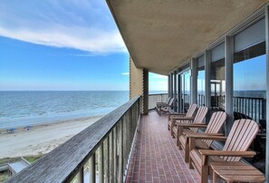 Enjoy the ocean view from this balcony with a clear view of the beach, featuring Adirondack chairs and a tiled floor.