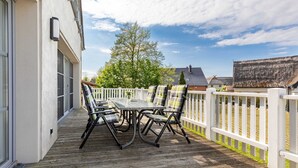 A wooden deck with a table and chairs, a white fence, and a tree in the background. - (2) Barbara, 3-room apartment, wheelchair accessible, ground floor - Ostseeferienhaus (Am Salzhaff)