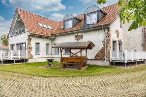 A house with a stone facade, a wooden pergola, and a paved courtyard.