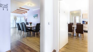 A modern interior with a dining area, wooden flooring, and a view through an open door. - (7) Lisa, 2-room apartment, loggia, upper floor - Ostseeferienhaus Drachenflieger Pepelow OFC (Am Salzhaff)