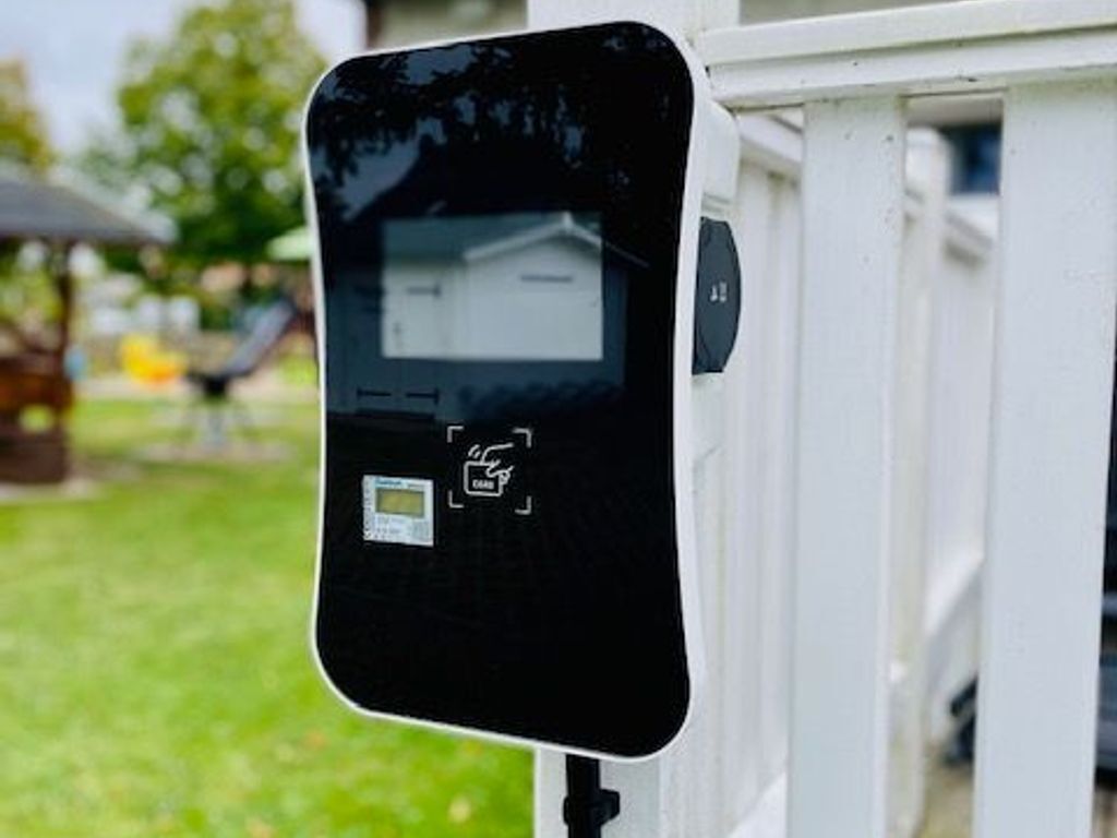 A black electronic device mounted on a white structure, possibly a security or control panel.