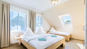 Un dormitorio con dos camas, un tragaluz y una ventana con cortinas.