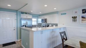 A modern kitchen with white cabinets, a stainless steel refrigerator, and a microwave.