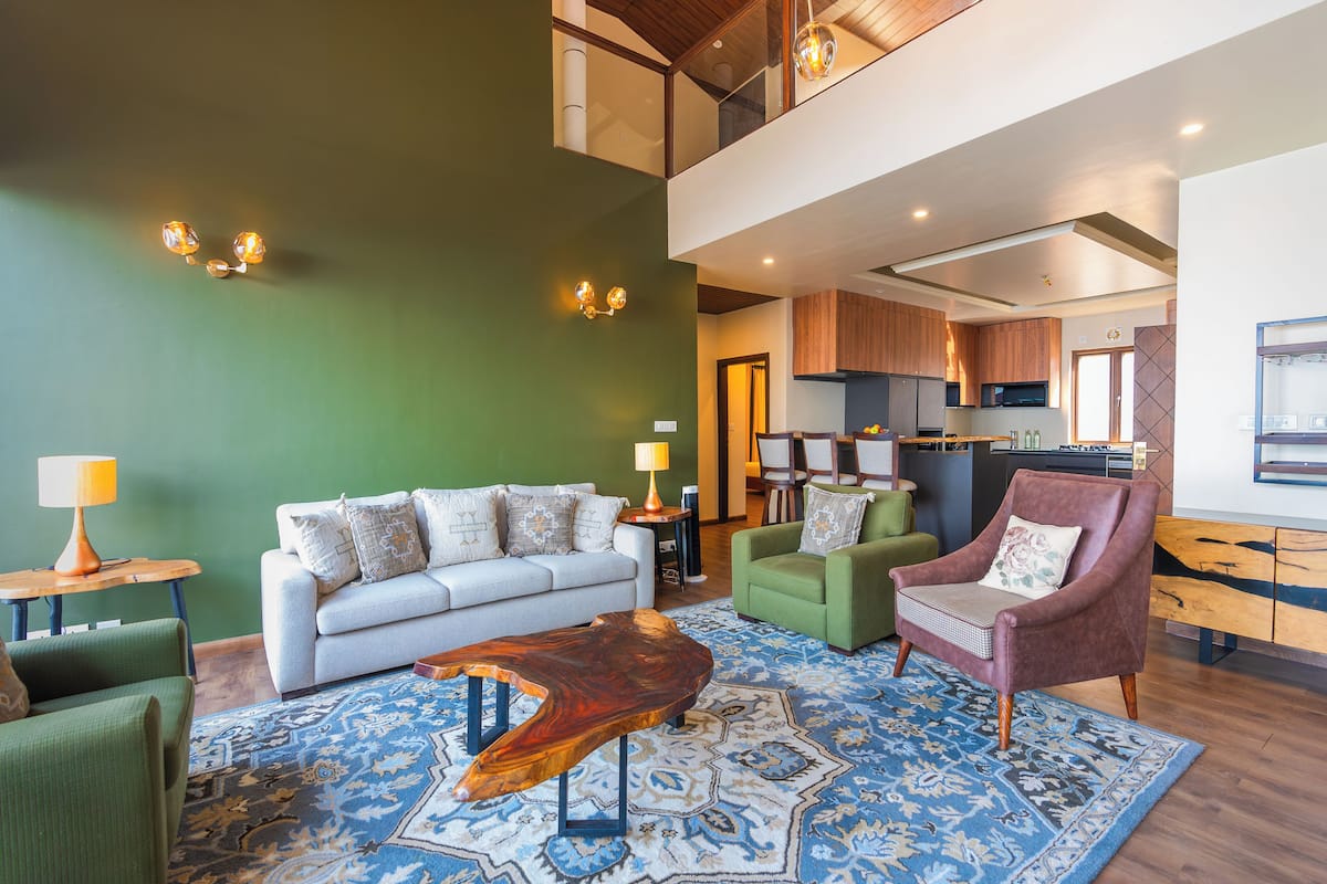 A modern living room with a sofa, armchairs, a coffee table, and a patterned rug.