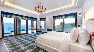Une chambre spacieuse avec un grand lit, un lustre et une vue sur la mer.