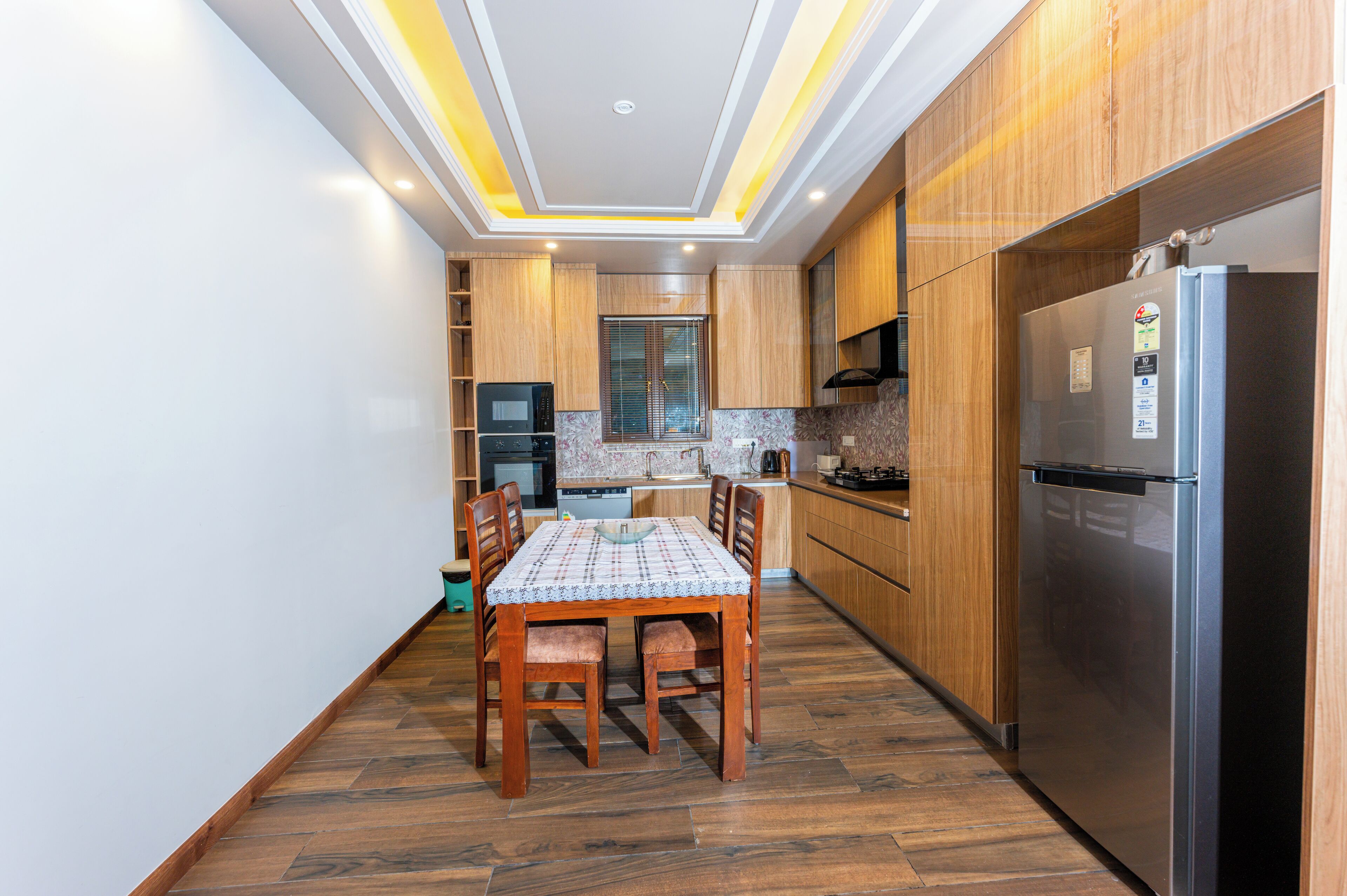 Una cucina moderna con mobili in legno, un frigorifero in acciaio inossidabile e un tavolo con sedie.