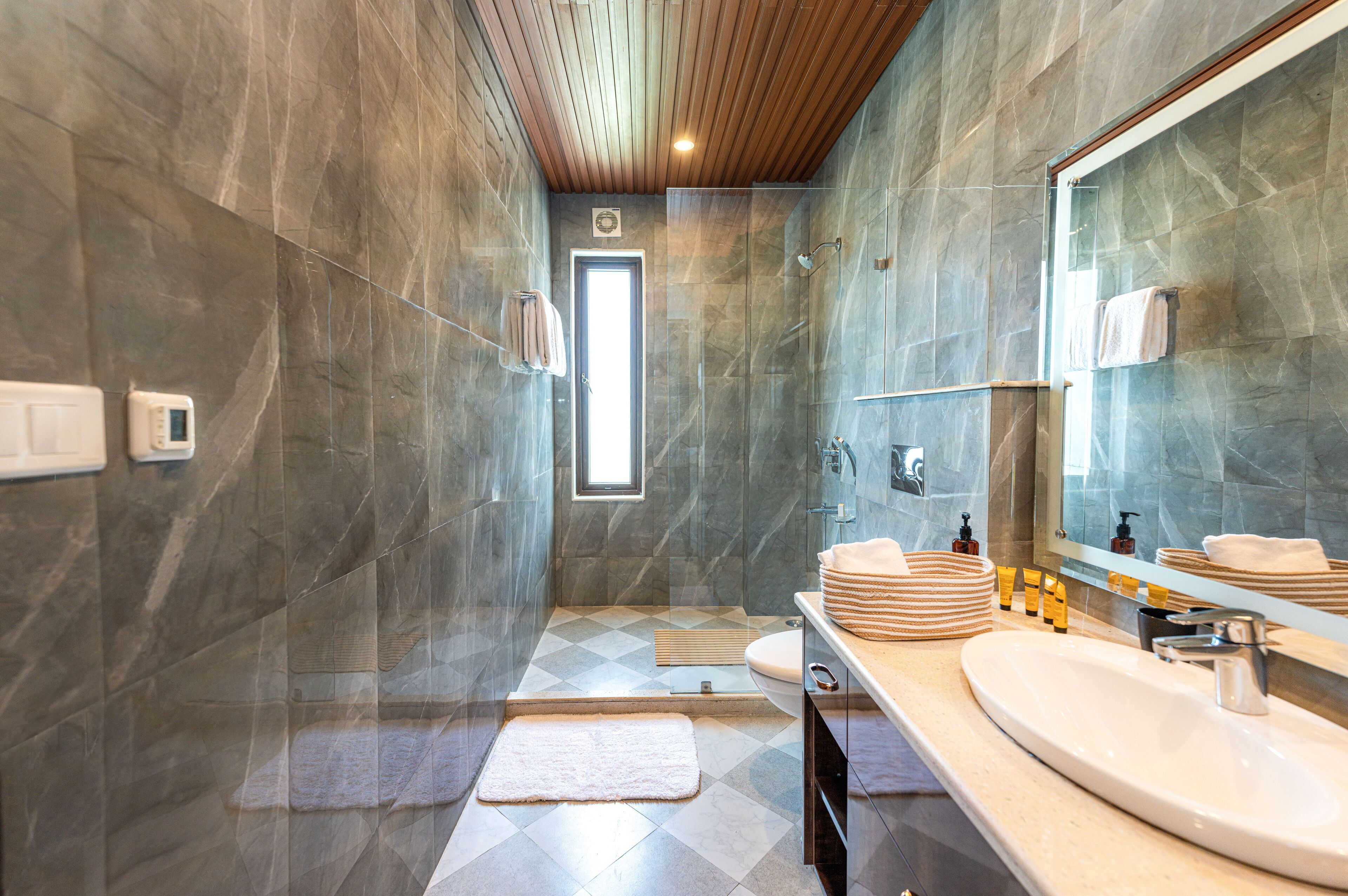 A modern bathroom with a large mirror, a sink, and a shower area.