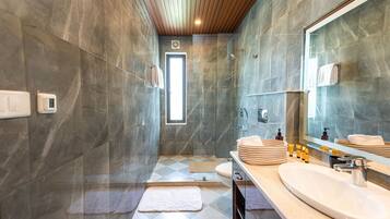 A modern bathroom with a large mirror, a sink, and a shower area.