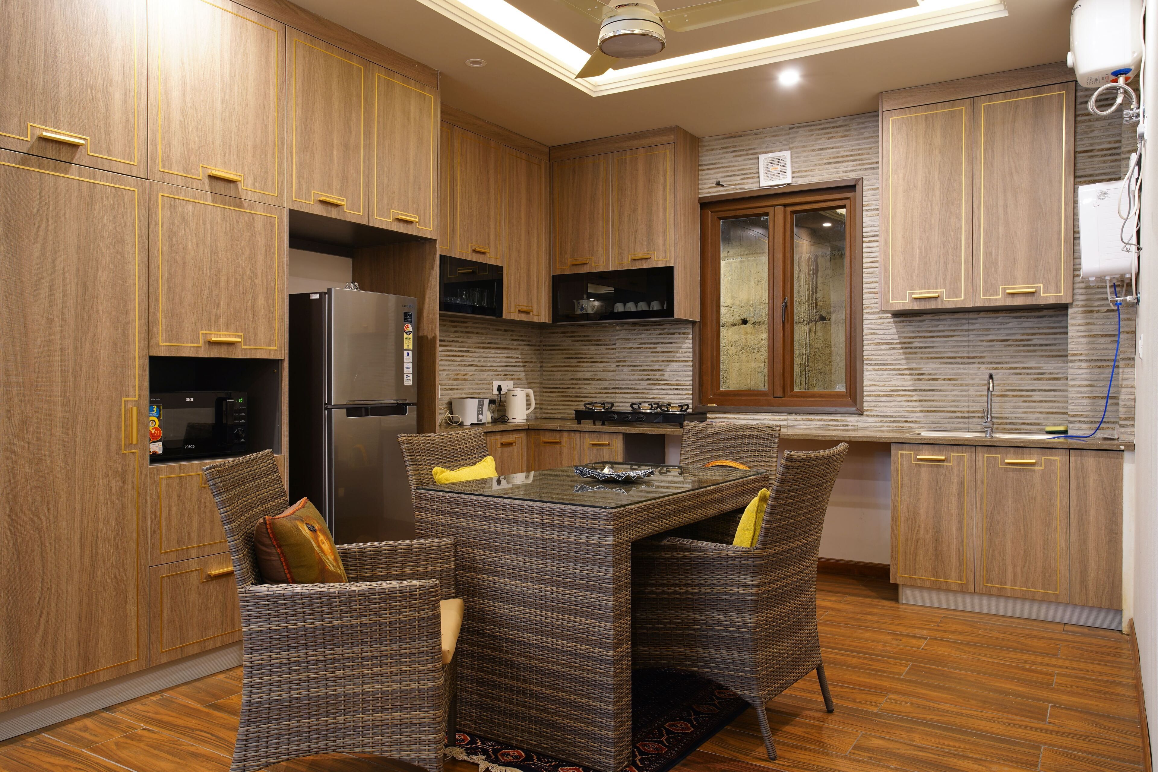 A modern kitchen with wooden cabinets, a built-in refrigerator, a gas stove, and a dining area with wicker chairs.