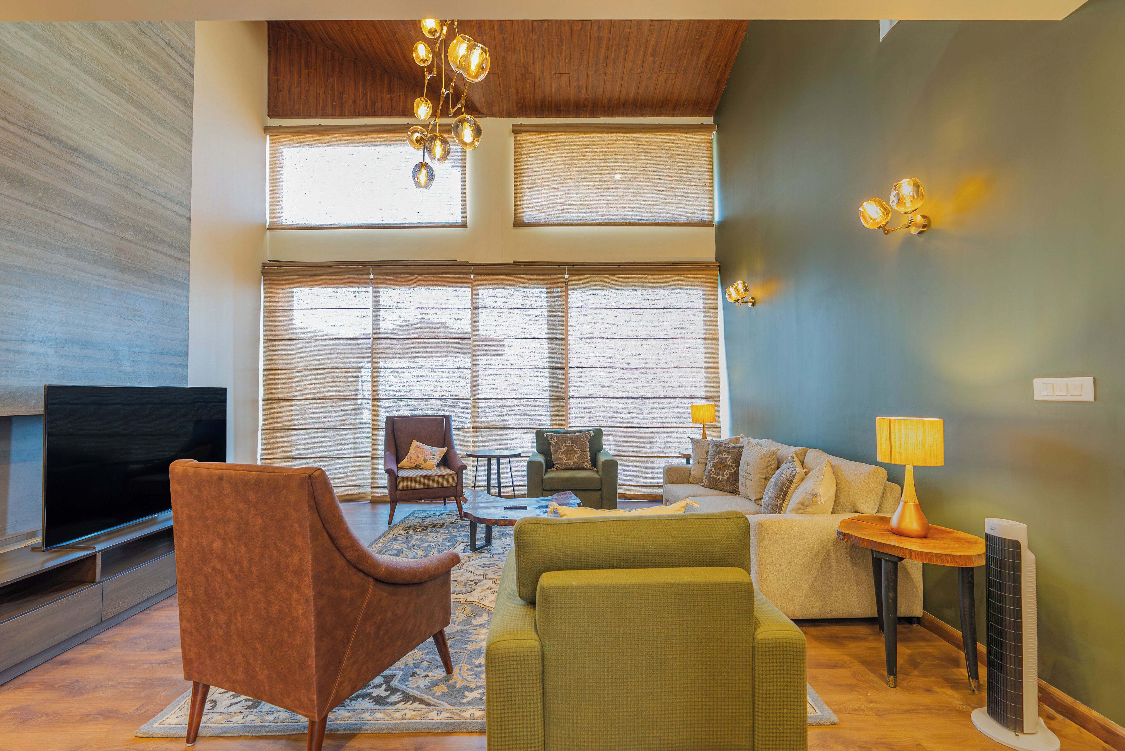 A spacious living area with a flat-screen TV, comfortable seating, large windows, and a ceiling fan.