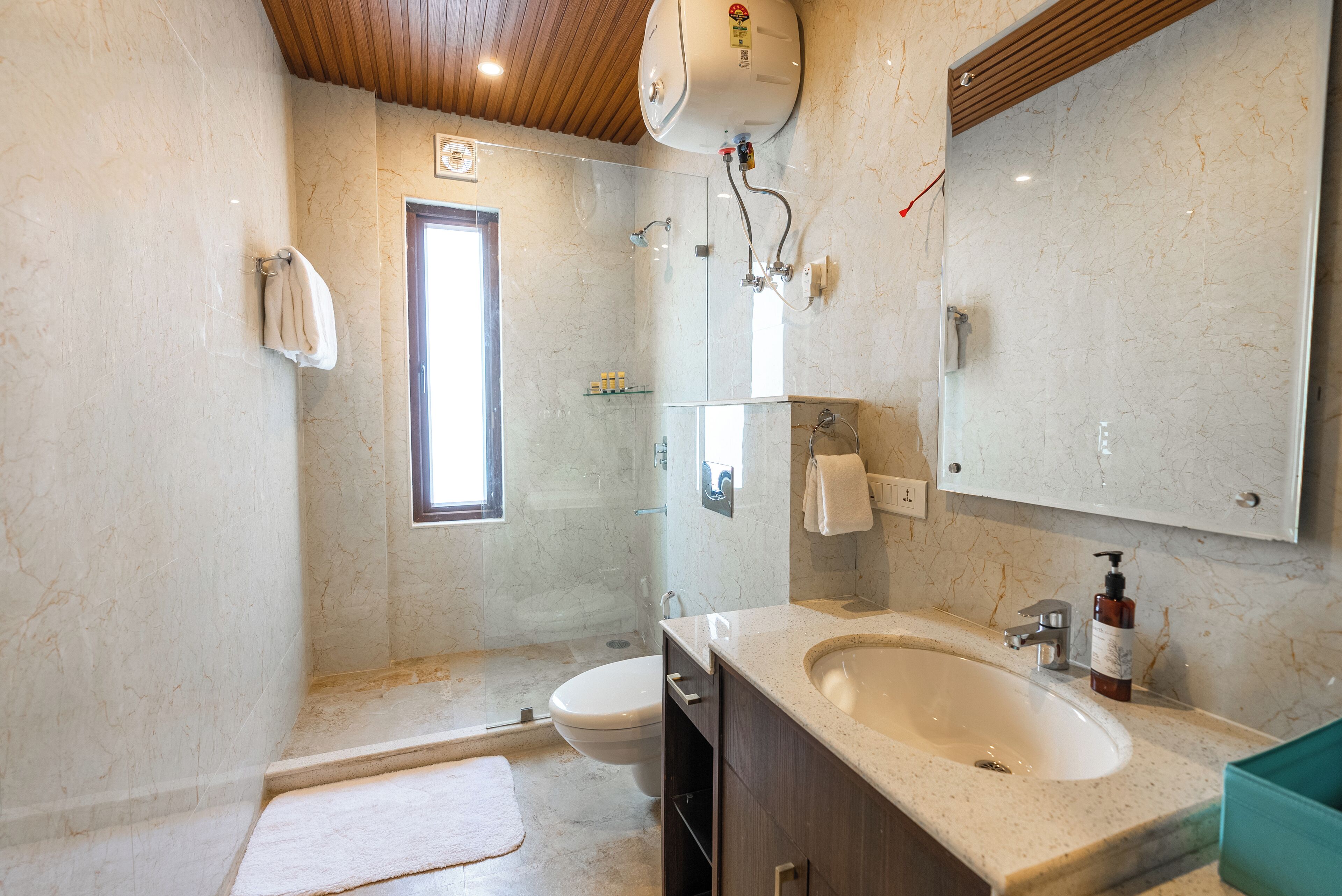 A bathroom with a shower, toilet, sink, and a large mirror.