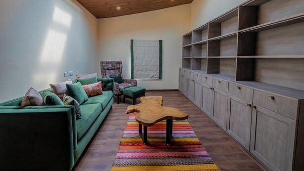 A modern living room with a green sofa, a wooden coffee table, and a colorful rug. - The Manor Luxury Apartments (Shimla)