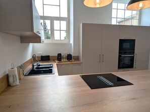 A modern kitchen with a large window, built-in oven, and a black countertop.