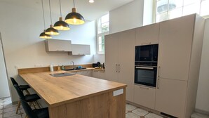 Een moderne keuken met een houten eiland, inbouwapparatuur en hanglampen.