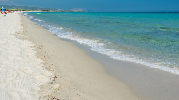 A beach with clear turquoise water, sandy shore, and distant hills. - One bedroom apartment (4 people) - Le Dimore di Budoni (Budoni)