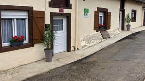 Une rangée de bâtiments traditionnels aux murs blancs et aux volets bruns, chacun doté d’une petite fenêtre et d’une porte.