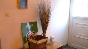 Une table en bois, un panier tressé, une branche décorative, une bouteille de gel hydroalcoolique et une pancarte avec le mot « GÎTE ».