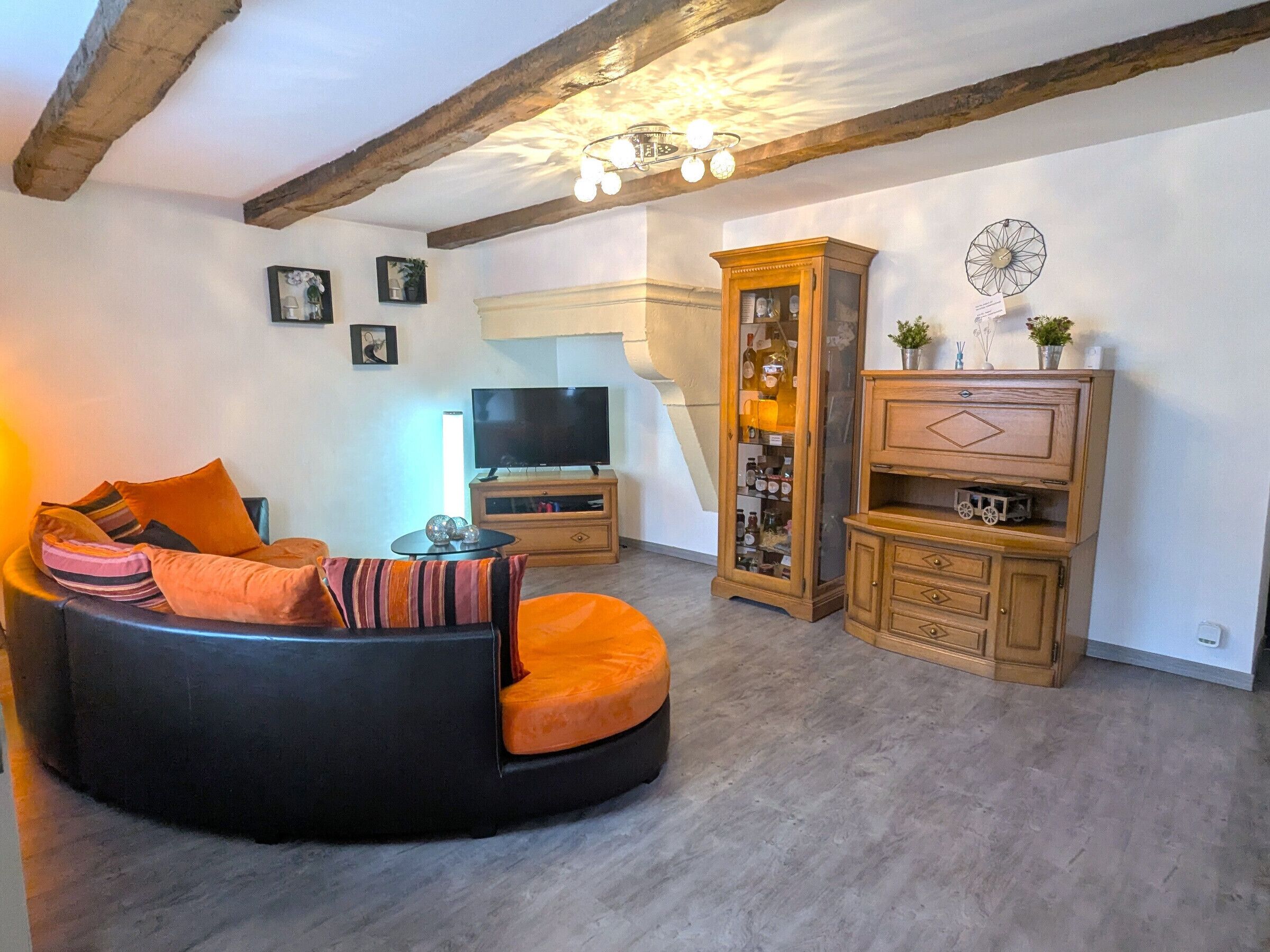 A living room with a black sofa, wooden cabinets, and a television.
