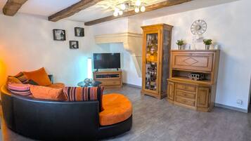 A living room with a black sofa, wooden cabinets, and a television.