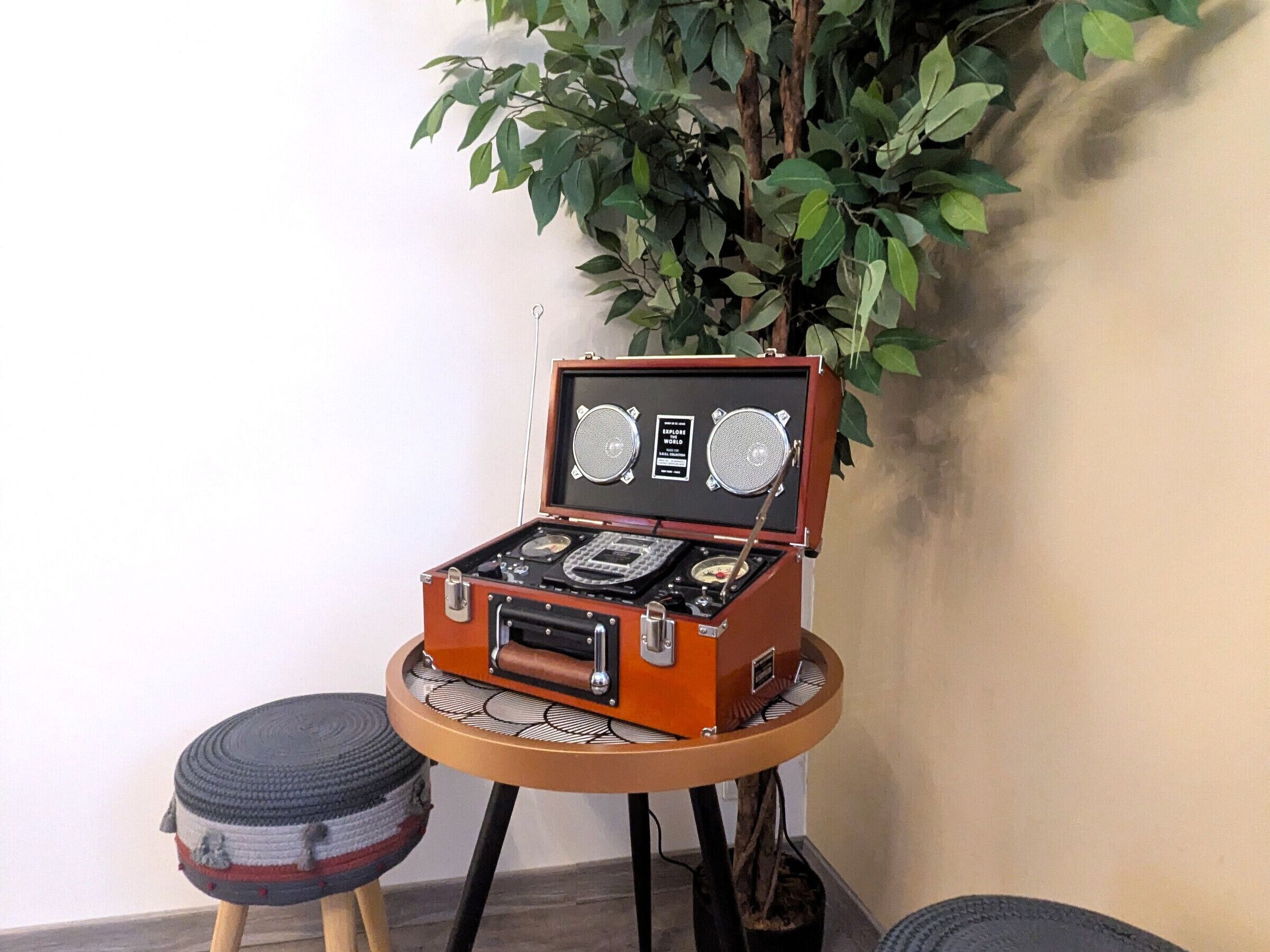 Une vieille valise transformée en enceinte, avec un tourne-disque posé sur une petite table ronde.