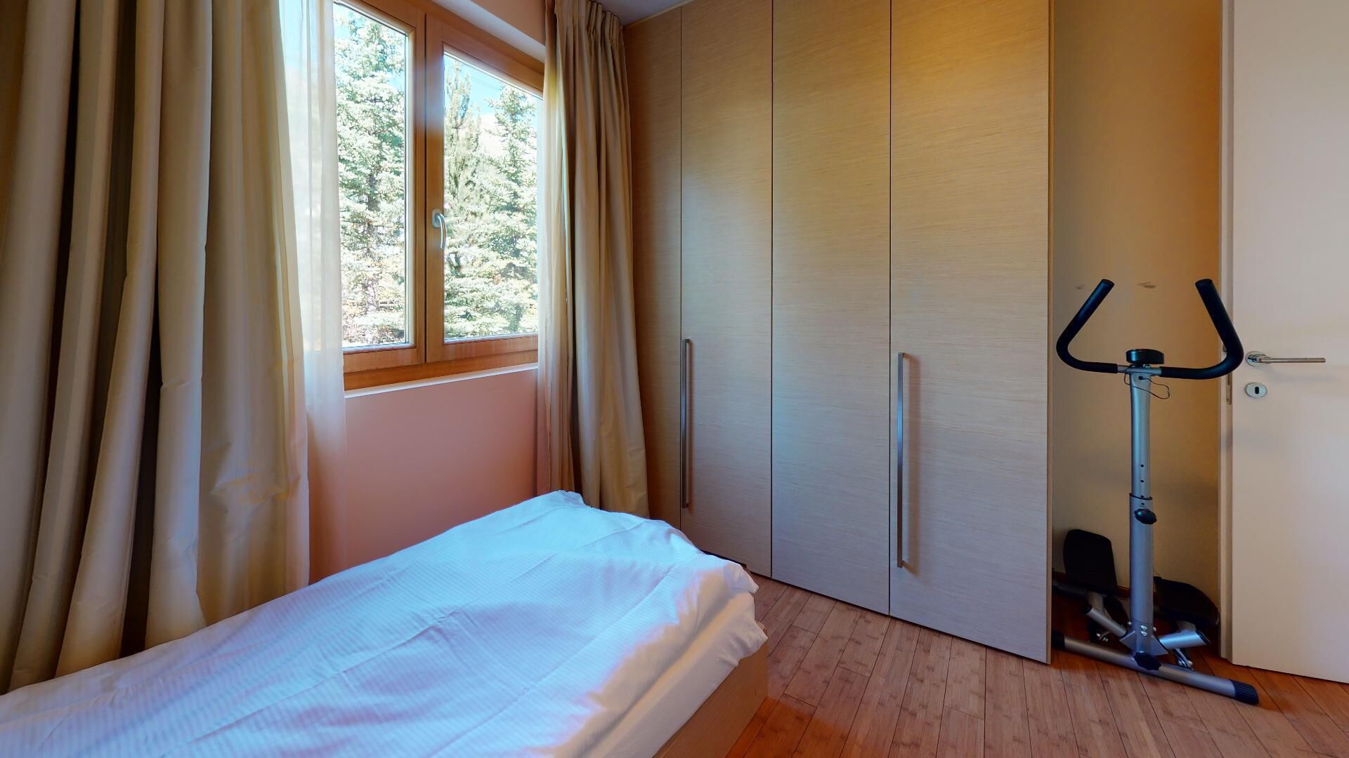 Een slaapkamer met een bed, een kledingkast en een hometrainer.