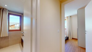 A modern apartment with a large window, a door leading to another room, and a visible balcony. - Modern 3½ room flat on the ground floor, approx. (Madulain)