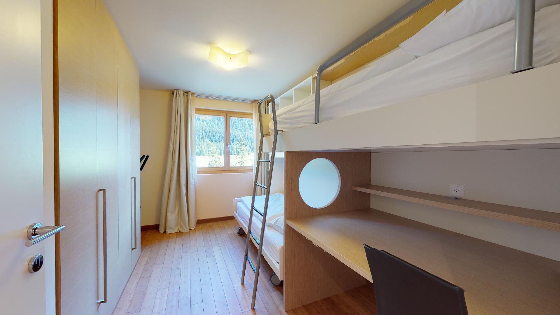 Une chambre avec un lit superposé, une fenêtre, une porte et une échelle.