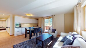 A modern apartment with a dining area, kitchen, and a living room with a sofa and a table. - Modern 3½ room flat on the ground floor, approx. (Madulain)