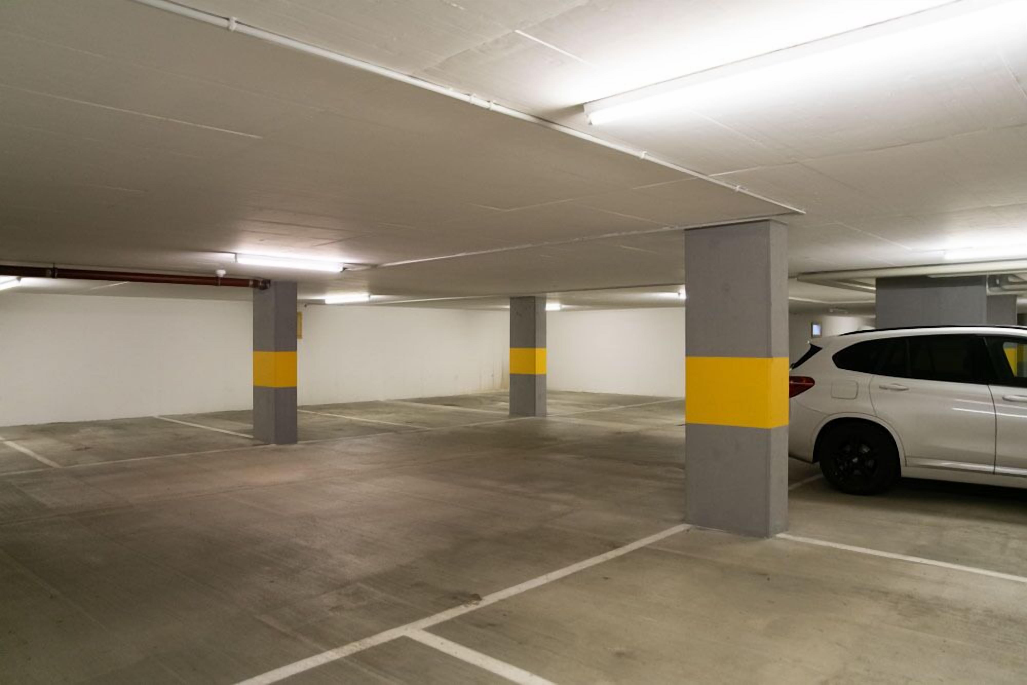 An indoor parking garage with concrete pillars and white walls.