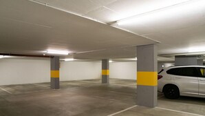 An indoor parking garage with concrete pillars and white walls. - Modern 3½ room flat on the ground floor, approx. (Madulain)