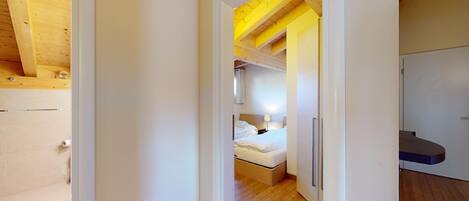 Ein Hotelzimmer mit Holzboden, einem Bett mit weißer Bettwäsche, einem Nachttisch und einem Beistelltisch.