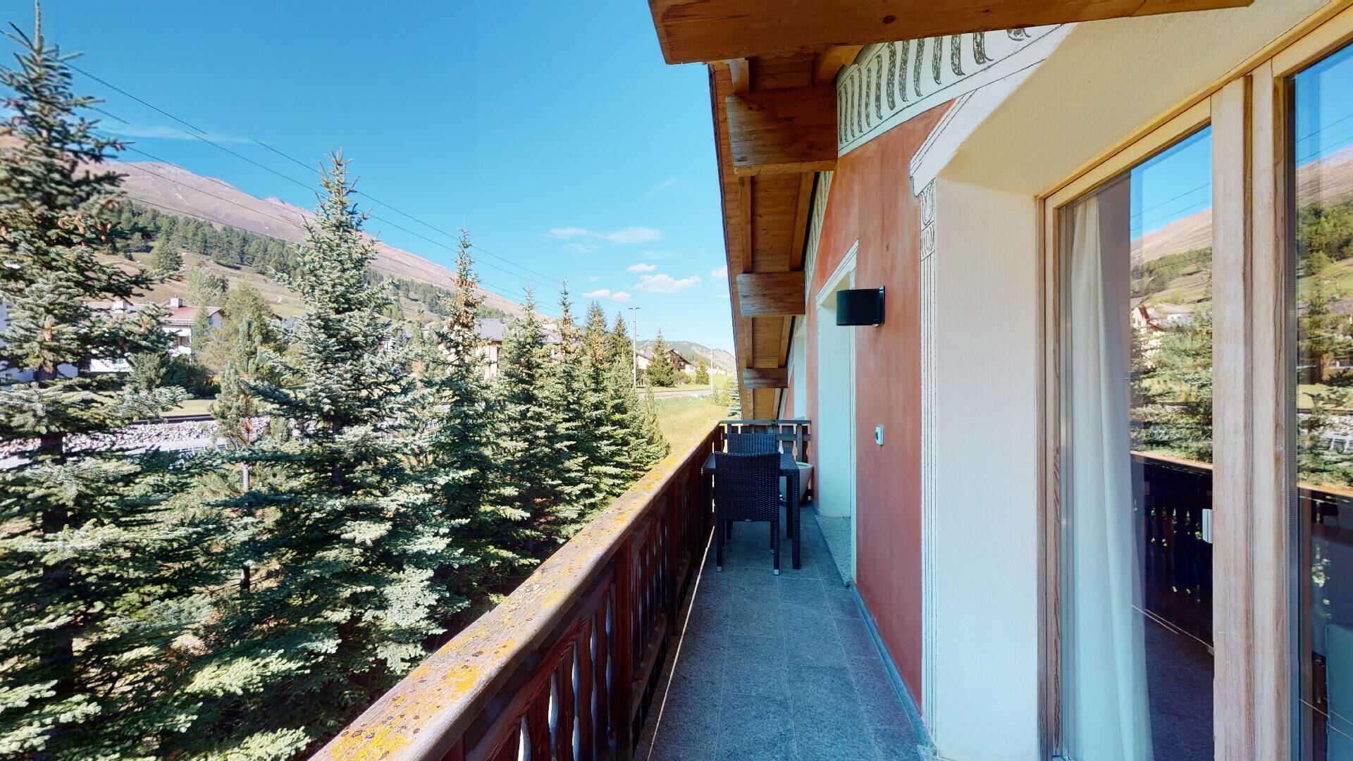 Un balcon offrant une vue sur une vallée boisée et des montagnes.