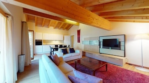 Uma sala de estar moderna com uma televisão grande, sofás brancos, uma mesa de centro e um tapete vermelho.