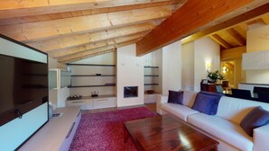 Uma sala de estar moderna com teto de madeira, uma televisão de tela plana, um sofá, uma mesa de centro e estantes embutidas.