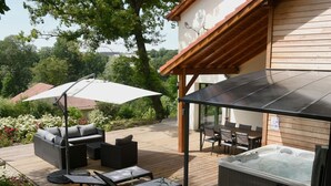 Un patio exterior con un jacuzzi, zona de estar y sombrillas.