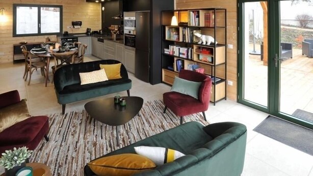 Un espacio de sala acogedor con un sofá, sillones, una mesa de centro y una estantería.