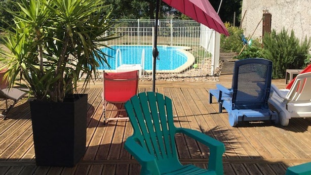 A wooden deck with a pool, green chairs, and a red umbrella. - Spacious Gîte with Private Pool, Near Nature Park & Attractions in Lorraine (Athienville)
