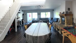 A spacious living area with a high ceiling, a dining table, sofas, and a foosball table. - Spacious Gîte with Private Pool, Near Nature Park & Attractions in Lorraine (Athienville)