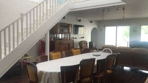 A dining area with a high ceiling, a staircase, and a kitchen area with wooden cabinets. - Spacious Gîte with Private Pool, Near Nature Park & Attractions in Lorraine (Athienville)