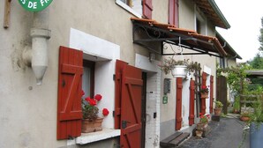 A building with red shutters, a bench, and potted plants.