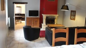 A living room with a fireplace, a television, and a dining area with a table set for two.