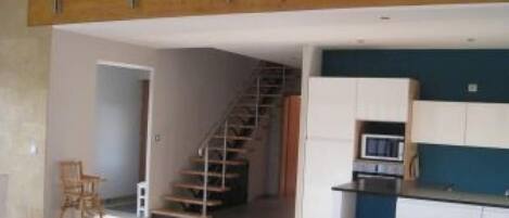 Un apartamento moderno con sala de estar, cocina y una escalera que conduce a un nivel superior.