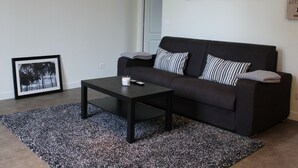 Ein modernes Wohnzimmer mit einer schwarzen Couch, einem Couchtisch und einem gerahmten Bild an der Wand.