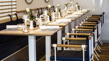 Una larga mesa de comedor con sillas, un banco y una pared con elementos decorativos.