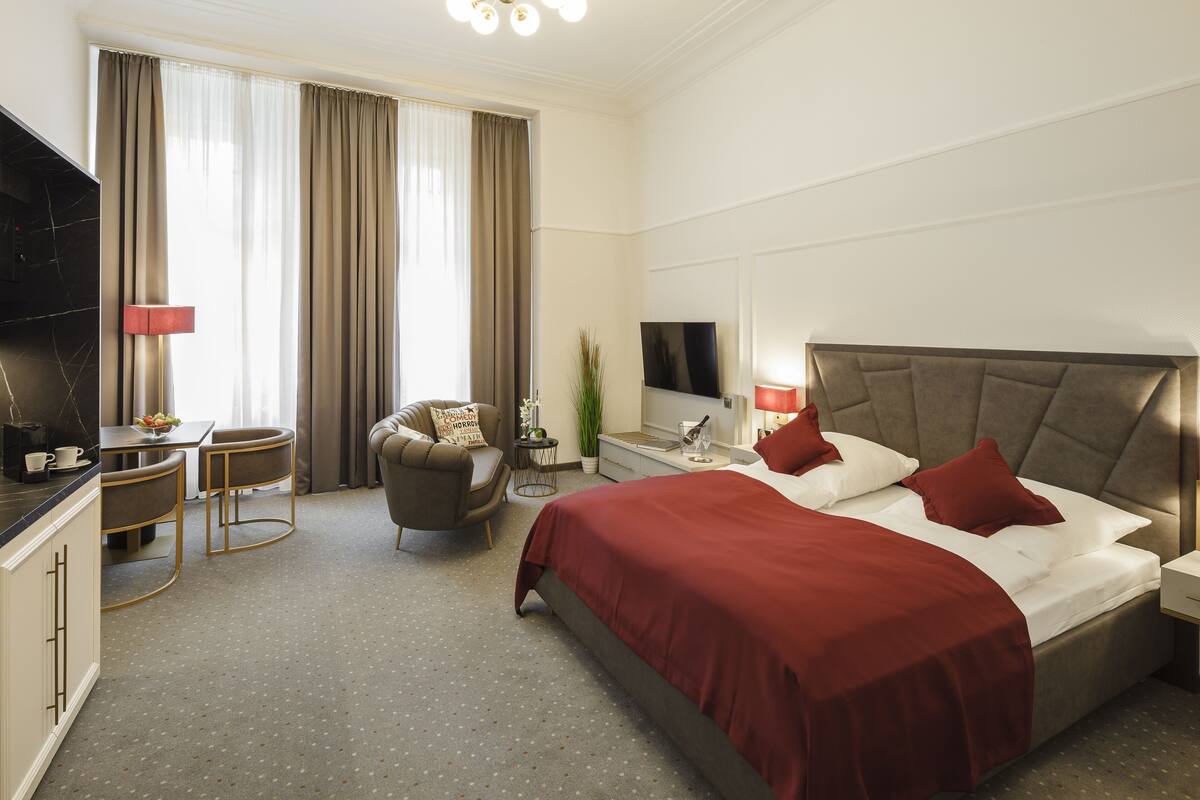 Une chambre d’hôtel avec un grand lit, une télévision, un bureau avec une chaise et une petite table avec une plante.